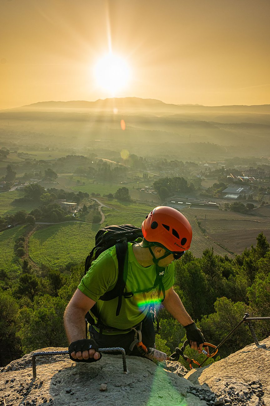 man summits a climb in golden hour above a spanish landscape